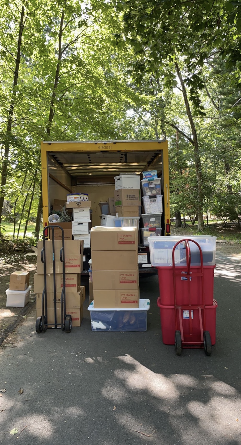 Moving boxes and storage bins are organized for loading into a moving truck during a residential relocation.