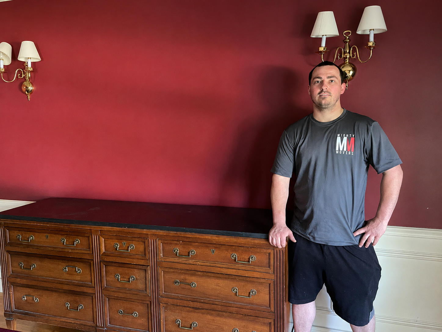 Mighty Movers professional standing beside a large wooden dresser during a residential furniture move.